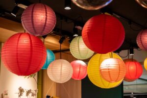Colourful paper lanterns hanging from a ceiling, creating a warm, festive atmosphere in an interior space.