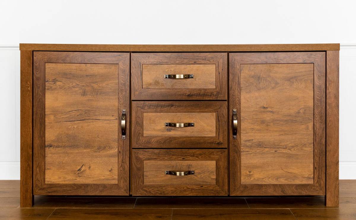 Wooden sideboard cabinet with two doors and three drawers, featuring metal handles, against a white wall.