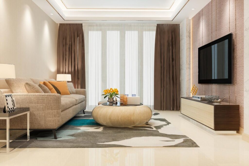 Modern living room with a beige sofa, patterned rug, and wall-mounted TV. Neutral tones and contemporary decor.