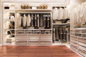 A spacious, well-organized walk-in wardrobe with clothes, shoes, and accessories neatly arranged on shelves and hangers.