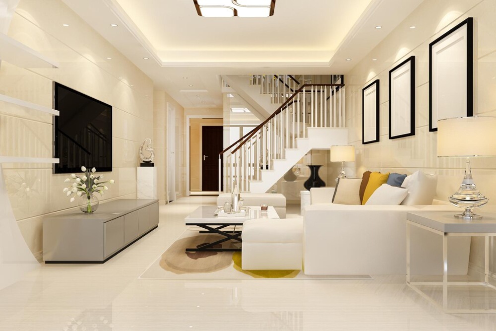  Luxurious living room interior with white sofas, large TV, and a staircase in a modern home.