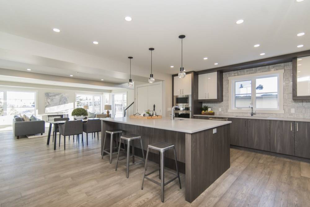 Modern open-plan kitchen and dining area with dark wood cabinetry, sleek white island, and ample natural light.