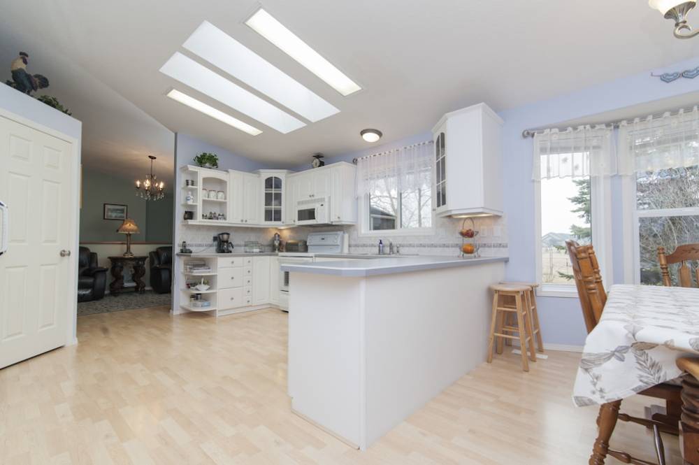  Bright, spacious kitchen with white cabinets, a central island, skylight windows, and adjoining dining area.