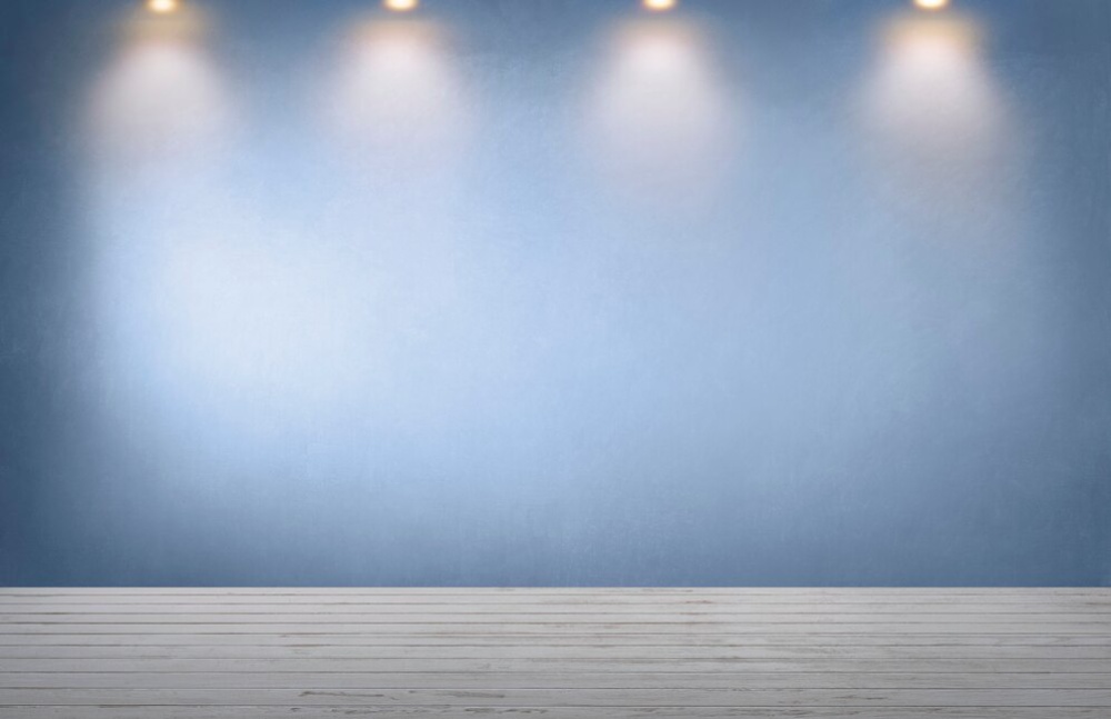  Empty room with a blue wall, wooden floor, and three ceiling spotlights.