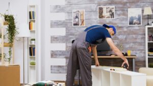 A craftsman measuring a white shelf in a stylishly decorated room.