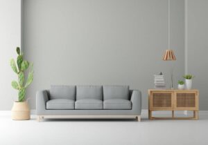 Minimalist living room with a grey sofa, wooden cabinet, hanging lamp, and indoor plants.