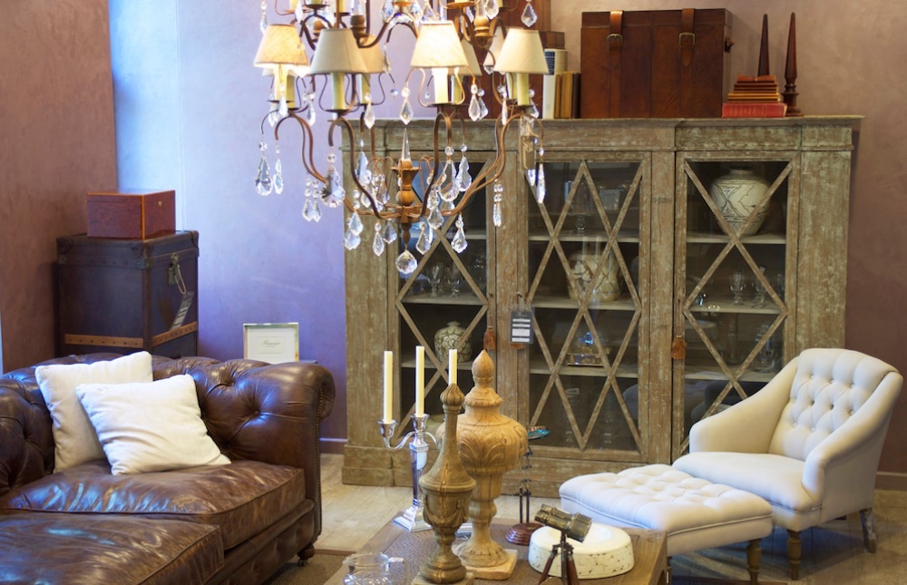  Elegant living room with leather sofa, white armchair, wooden cabinet, and crystal chandelier.