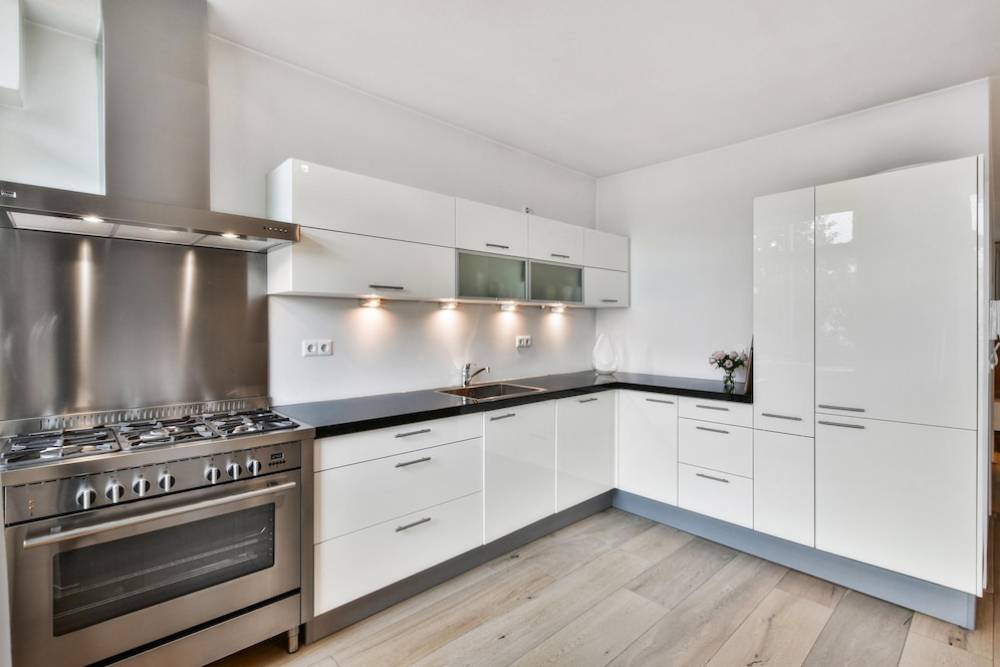  Modern kitchen with white cabinetry, stainless steel appliances, and wood flooring.