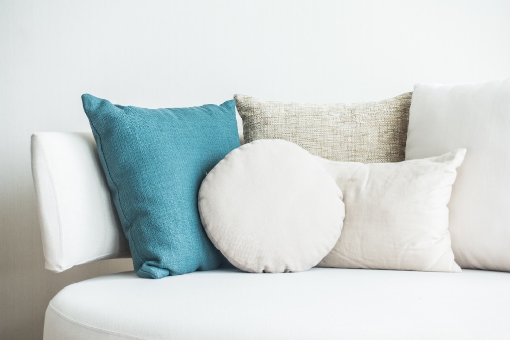  A white sofa adorned with a collection of pillows in shades of blue, white, and beige.