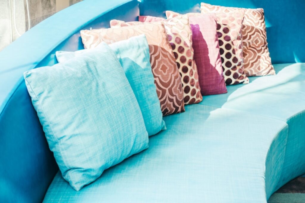 Blue sofa lined with assorted patterned cushions in a bright, contemporary living room.
