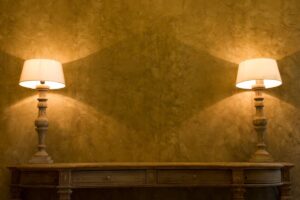 Two vintage lamps on a wooden console against a textured golden wall.