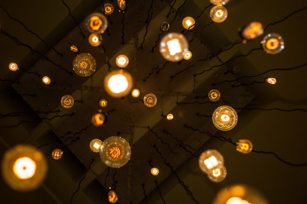  Illuminated round bulbs on strings against a dark background, creating a warm, glowing pattern from an aerial view.