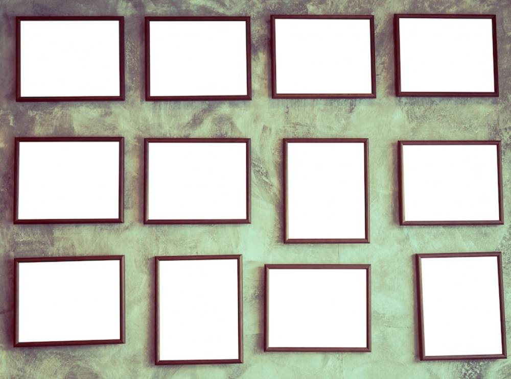  Multiple blank frames mounted on a textured green wall in an orderly arrangement.