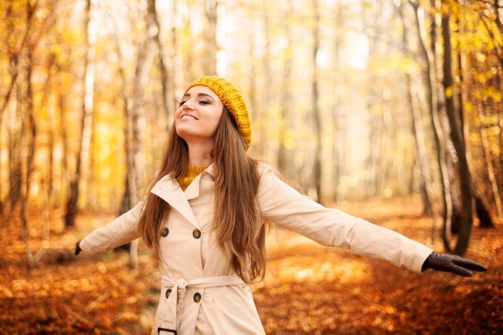   Young woman in a yellow hat enjoying a sunny autumn day in a forest.